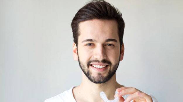 A young man holding Bruxism-Nightguards