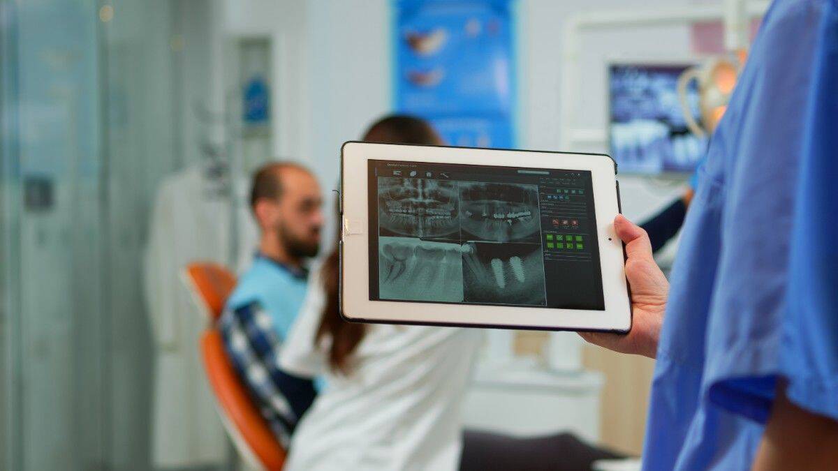 showing dental X-rays on tablet to patient